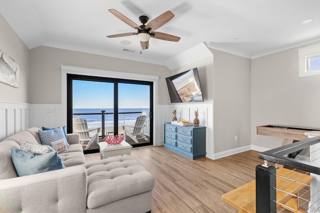 living room featuring visible vents, a ceiling fan, wainscoting, light wood-style flooring, and ornamental molding