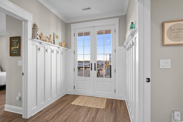 doorway featuring visible vents, ornamental molding, wood finished floors, and french doors