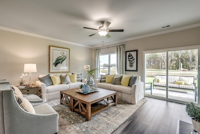 living area featuring wood finished floors, visible vents, and ornamental molding