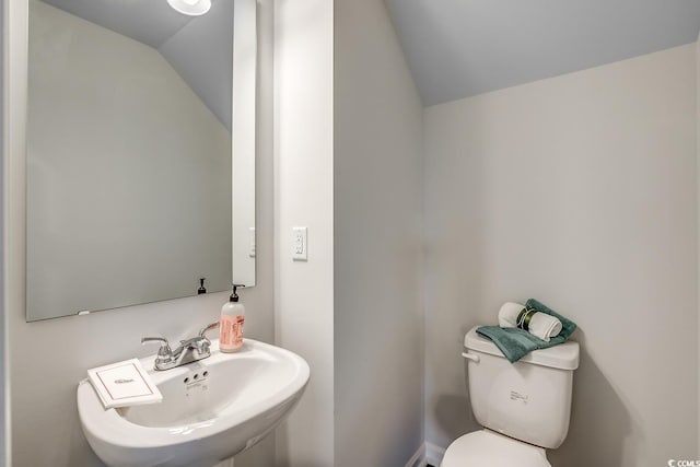 bathroom featuring a sink, toilet, and vaulted ceiling