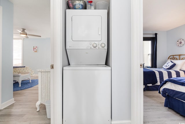 washroom with a ceiling fan, stacked washer / drying machine, baseboards, and light wood finished floors