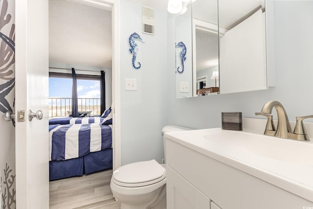 bathroom featuring visible vents, connected bathroom, toilet, wood finished floors, and vanity