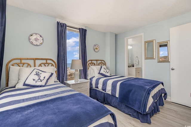 bedroom with light wood-style floors, a textured ceiling, and ensuite bathroom