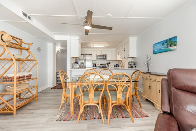 dining area with baseboards, a ceiling fan, visible vents, and light wood-style floors