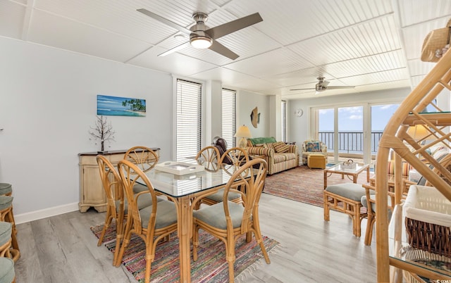 dining room with light wood finished floors, a ceiling fan, and baseboards