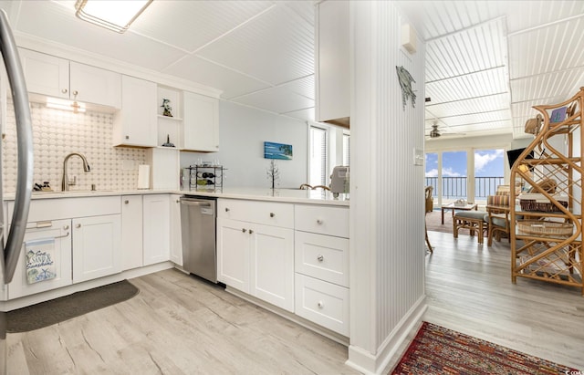 kitchen with dishwasher, light countertops, light wood finished floors, and a sink