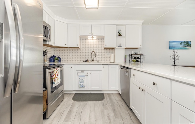 kitchen with appliances with stainless steel finishes, white cabinetry, a sink, and open shelves