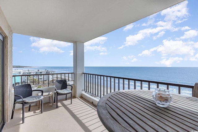 balcony with a water view and a view of the beach