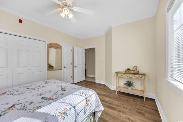 bedroom with crown molding, wood finished floors, baseboards, and a closet