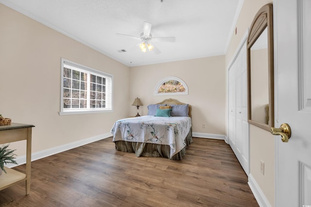 bedroom featuring visible vents, ceiling fan, baseboards, wood finished floors, and a closet