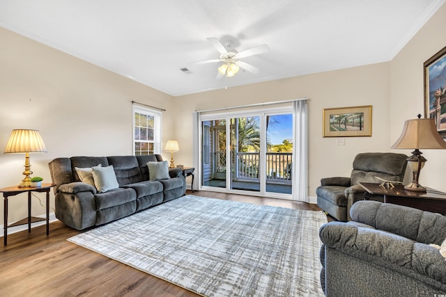 living room featuring ceiling fan, wood finished floors, baseboards, and ornamental molding