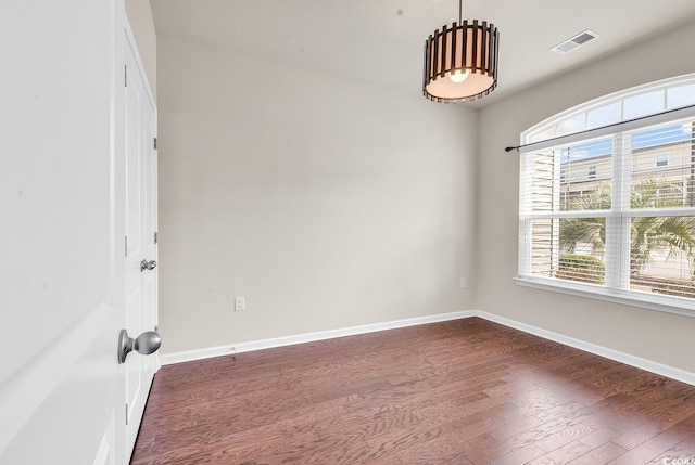 unfurnished room with baseboards, visible vents, and dark wood-style flooring