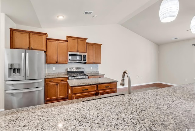 kitchen with brown cabinetry, visible vents, and stainless steel appliances