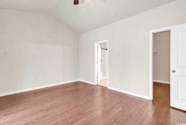 empty room featuring lofted ceiling, ceiling fan, baseboards, and wood finished floors