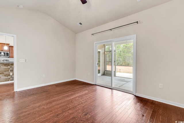 spare room featuring vaulted ceiling, hardwood / wood-style floors, visible vents, and baseboards