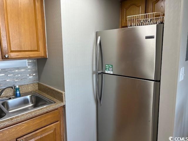 kitchen with decorative backsplash, a sink, and freestanding refrigerator