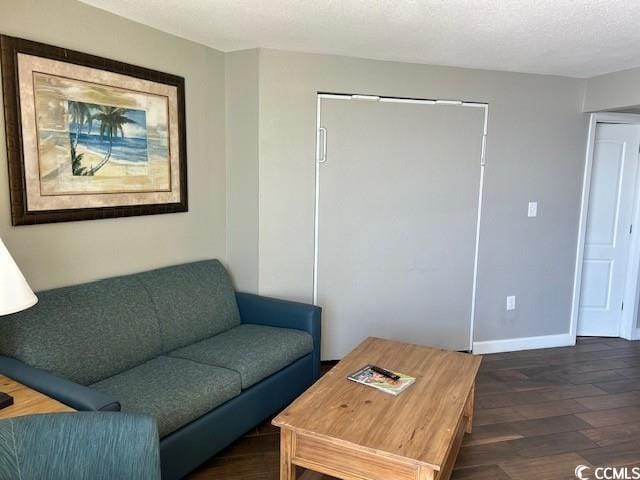 living area featuring a textured ceiling, dark wood-style flooring, and baseboards