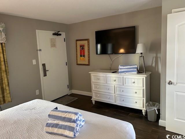 bedroom featuring baseboards and dark wood-type flooring