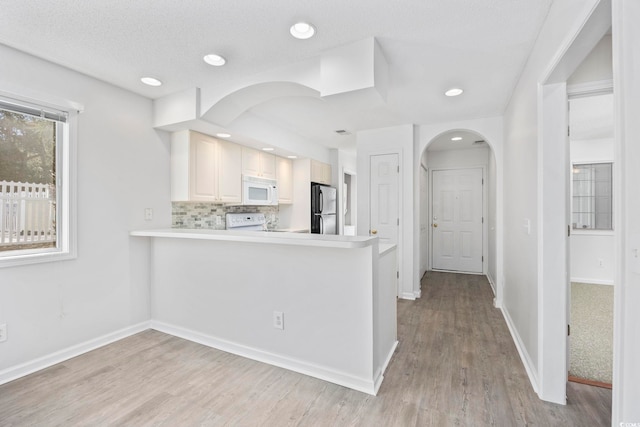 4430 Eastport Blvd Unit L5, Little River, SC 29566 - kitchen with arched walkways, light wood-type flooring, freestanding refrigerator, white microwave, and stove