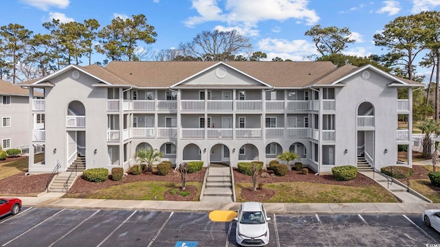 view of property with uncovered parking and stairs