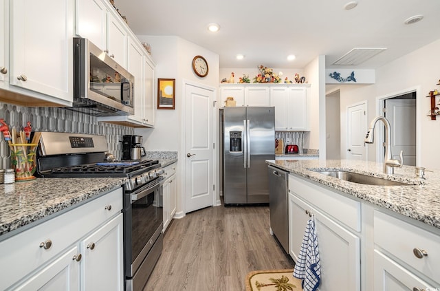 1881 Moonseed Dr, Longs, SC 29568 - kitchen featuring appliances with stainless steel finishes, a sink, white cabinets, light wood finished floors, and recessed lighting