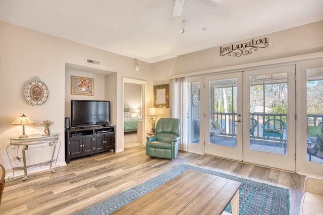 living area with french doors, visible vents, light wood finished floors, and ceiling fan