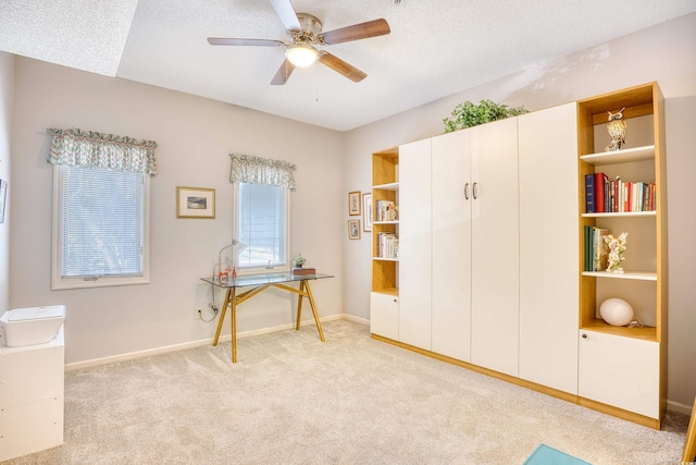 interior space featuring baseboards, light carpet, a textured ceiling, and ceiling fan