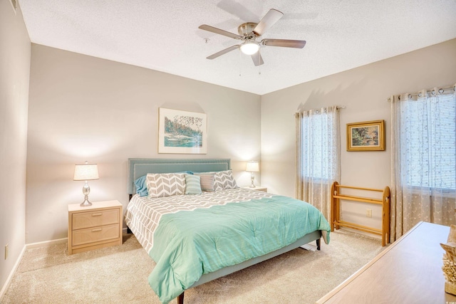 bedroom featuring light carpet, a textured ceiling, and baseboards