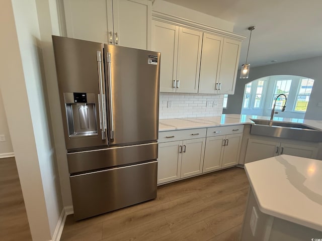 4008 Bucolic Loop, Myrtle Beach, SC 29588 - kitchen featuring stainless steel refrigerator with ice dispenser, a sink, wood finished floors, arched walkways, and decorative backsplash