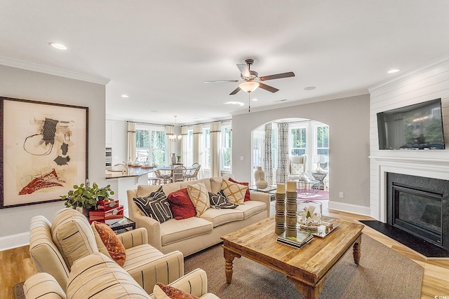 living room with baseboards, ornamental molding, recessed lighting, a fireplace, and wood finished floors