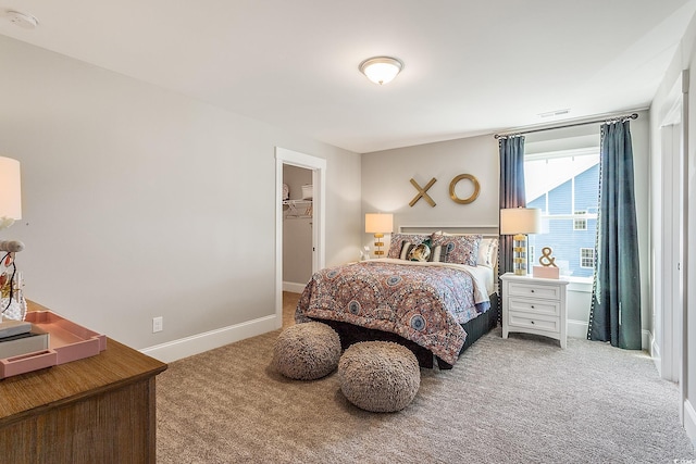 bedroom featuring visible vents, baseboards, a walk in closet, and carpet flooring