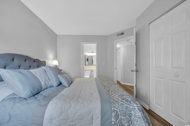 bedroom featuring visible vents, baseboards, ensuite bath, and dark wood finished floors