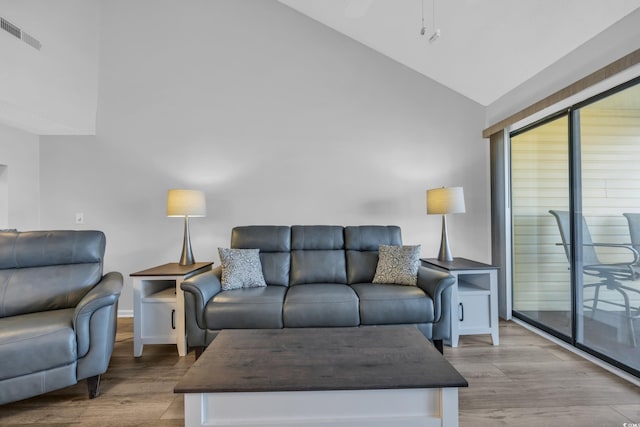 living area with visible vents, high vaulted ceiling, and wood finished floors