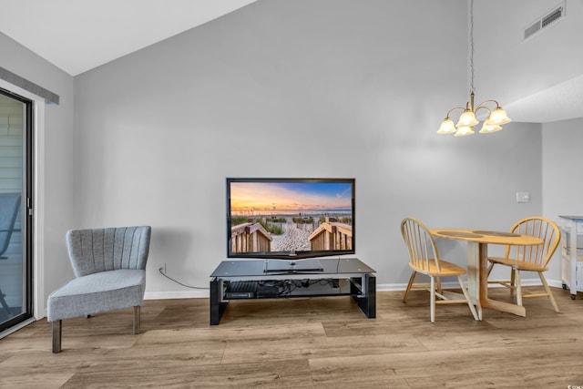 living area with a notable chandelier, wood finished floors, visible vents, and baseboards