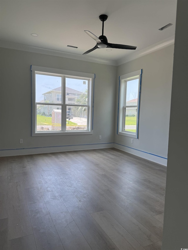spare room with plenty of natural light, crown molding, ceiling fan, and wood finished floors