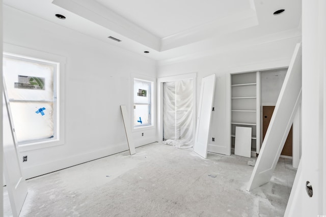 unfurnished bedroom featuring a raised ceiling and multiple closets