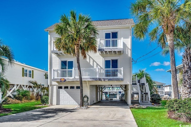 coastal home featuring a carport, driveway, stairway, and an attached garage