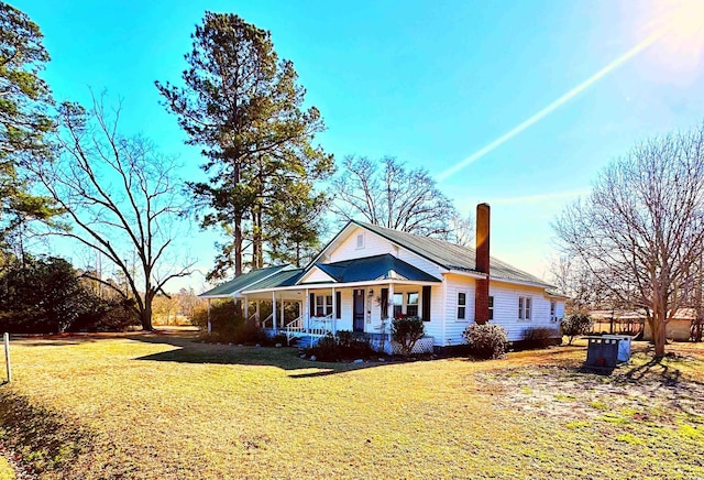 view of front of home featuring a porch, a chimney, and a front yard