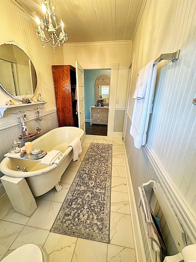 bathroom with wooden ceiling, a soaking tub, marble finish floor, an inviting chandelier, and crown molding