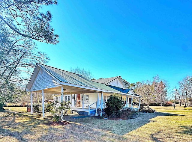 view of side of property featuring metal roof, a porch, and a yard