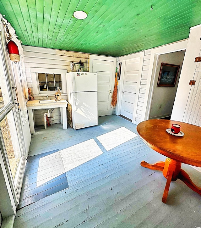 kitchen featuring freestanding refrigerator, wooden ceiling, a sink, and hardwood / wood-style flooring