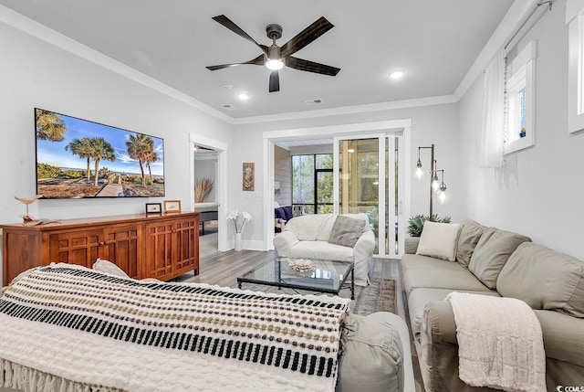 living room featuring a ceiling fan, wood finished floors, visible vents, and ornamental molding