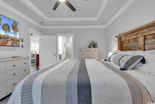 bedroom featuring a tray ceiling, connected bathroom, and a ceiling fan