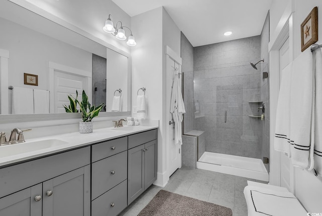 full bathroom featuring double vanity, tile patterned floors, a tile shower, and a sink