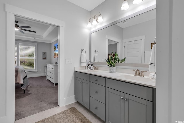 bathroom with a sink, a tray ceiling, connected bathroom, and double vanity