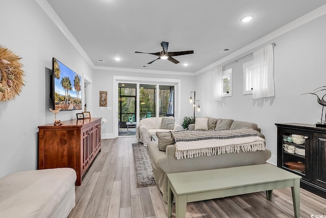 bedroom featuring multiple windows, crown molding, light wood-type flooring, and access to outside