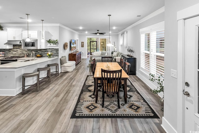 dining room with crown molding, light wood-style floors, and baseboards