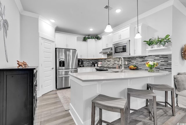 kitchen featuring visible vents, a peninsula, stainless steel appliances, under cabinet range hood, and tasteful backsplash