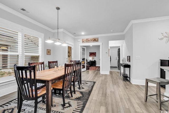 dining area featuring visible vents, light wood-style flooring, baseboards, and ornamental molding