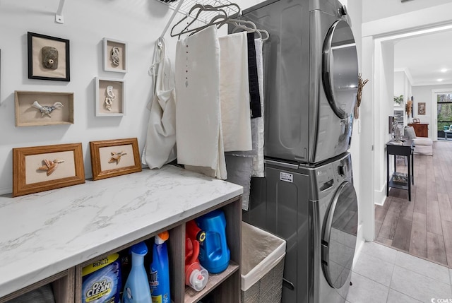 washroom with light tile patterned floors, laundry area, crown molding, and stacked washer / drying machine